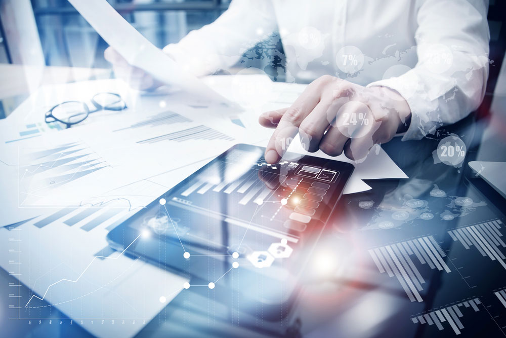 man using a tablet while holding paper