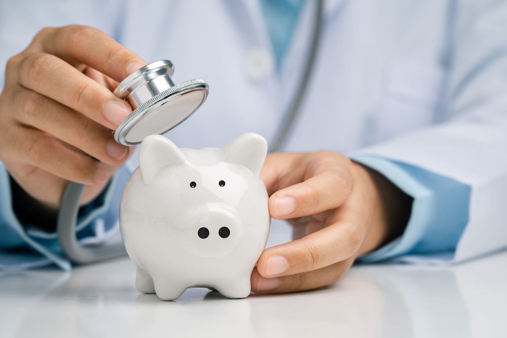 doctor using a stethoscope to check the piggy bank